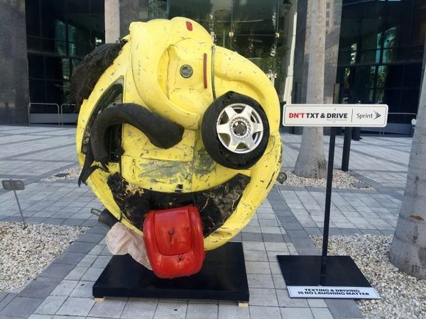 Sculpture of an emoji built from the twisted metal of a wrecked car