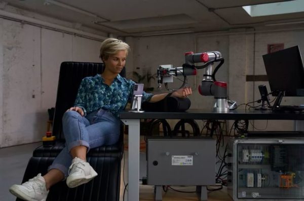 A robotic arm tattooing a person’s arm