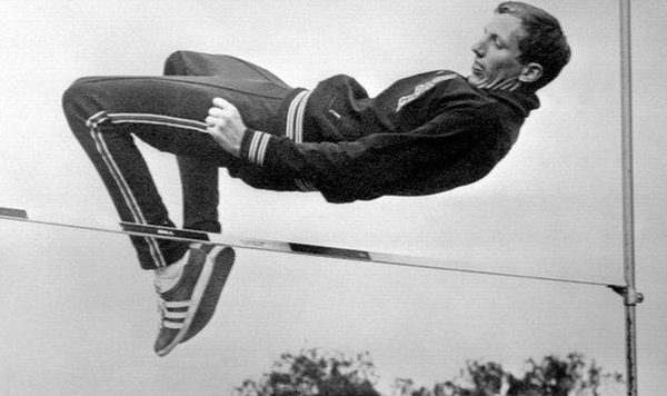 A high jumper clearing the bar backwards using the Fosbury Flop