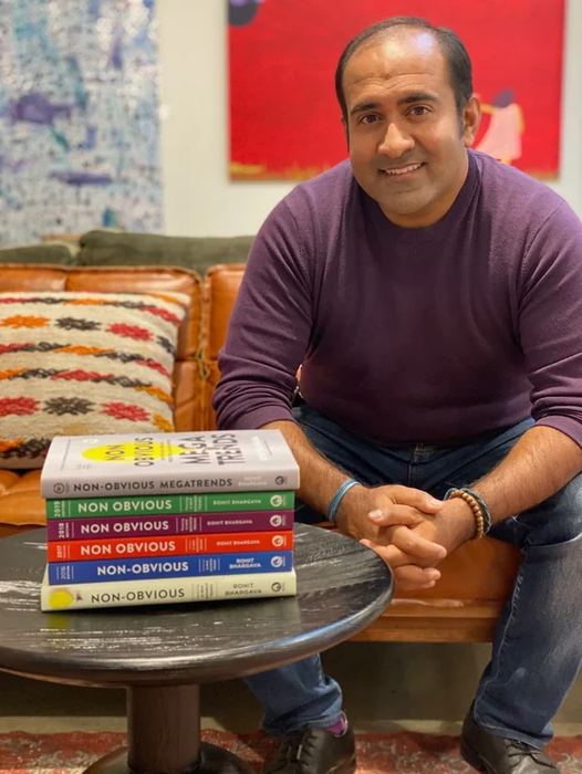 Rohit beside a stack of the Non-Obvious trend books