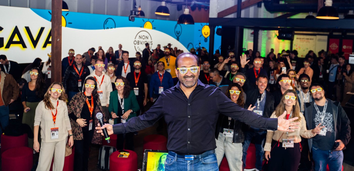 Rohit Bhargava with arms outstretched on stage in yellow Non-Obvious glasses, greeting a crowd wearing matching glasses